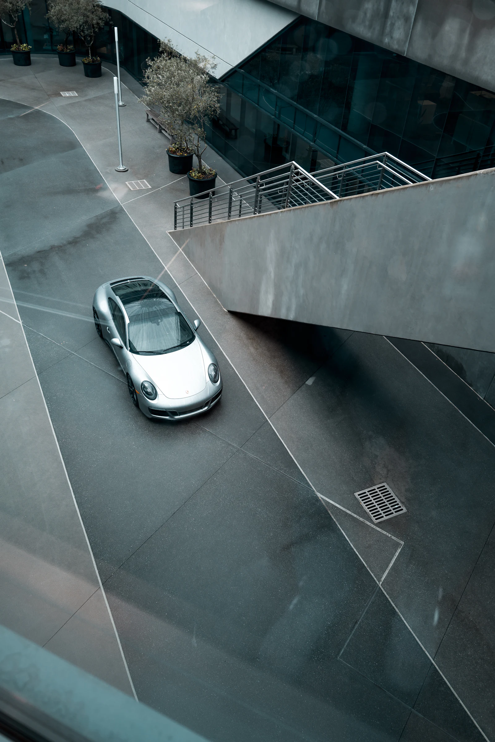 Silver sports car photographed from above in an architectural courtyard